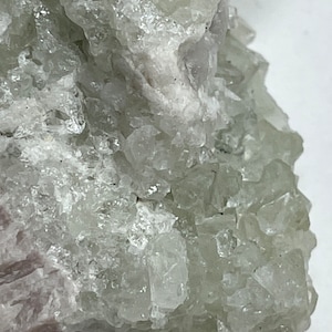 Puede incluir: Un cúmulo de cristales de fluorita verdes y blancos con una textura rugosa y natural. Los cristales están agrupados en un patrón aleatorio, creando una exhibición única e interesante.