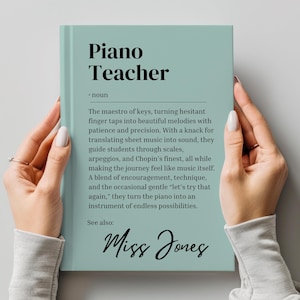 May include: A teal blue book with the title "Piano Teacher" and the text "The maestro of keys, turning hesitant finger taps into beautiful melodies with patience and precision. With a knack for translating sheet music into sound, they guide students through scales, arpeggios, and Chopin's finest, all while making the journey feel like music itself. A blend of encouragement, technique, and the occasional gentle 'let's try that again,' they turn the piano into an instrument of endless possibilities. See also: Miss Jones"
