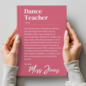 Op de afbeelding: Een roze boek met de titel "Dance Teacher" en een definitie van het woord. Het boek bevat ook de naam "Miss Jones" in een decoratief lettertype.