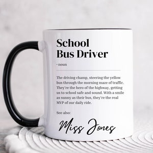 Peut inclure: Une tasse en céramique blanche avec une poignée noire. La tasse a un bord noir et présente une définition de "Conducteur de bus scolaire" avec le texte "Voir aussi : Miss Jones".