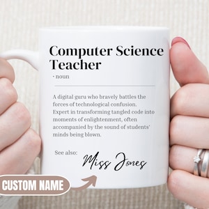 May include: White ceramic mug with a black design that reads "Computer Science Teacher" and defines the term as "A digital guru who bravely battles the forces of technological confusion. Expert in transforming tangled code into moments of enlightenment, often accompanied by the sound of students' minds being blown." The mug also says "See also: Miss Jones" with an arrow pointing to the text. The mug is being held by a person's hands.