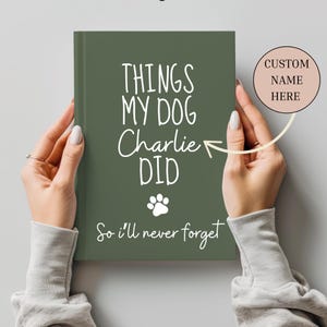 Op de afbeelding: Een groen notitieboek met de tekst "Things My Dog Charlie Did So I'll Never Forget" in wit. Er is een poot afdrukpictogram onder de tekst. Een witte ovaal met de tekst "CUSTOM NAME HERE" bevindt zich in de rechterbovenhoek van de afbeelding.
