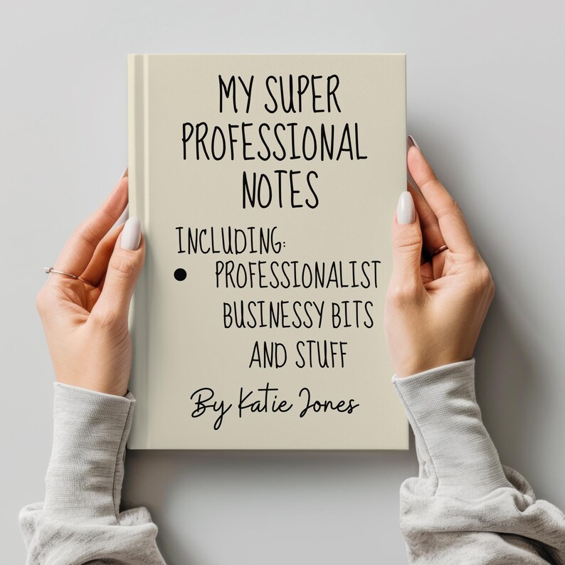 May include: A beige notebook with the text "MY SUPER PROFESSIONAL NOTES INCLUDING: PROFESSIONALIST BUSINESSY BITS AND STUFF By Katie Jones" written in black.
