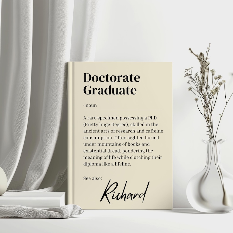 以下が含まれることがあります： ベージュのカードに「Doctorate Graduate」というテキストと、その用語の定義が書かれています。定義は、博士号を取得し、研究とカフェイン摂取に精通した人物について説明しています。カードの下部には「Richard」という名前も記載されています。