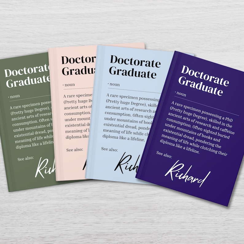 以下が含まれることがあります： 表紙に「Doctorate Graduate」と書かれた、4冊の色が異なる本。各本には「Doctorate Graduate」の定義と、ページの下部に「Richard」という名前が書かれている。