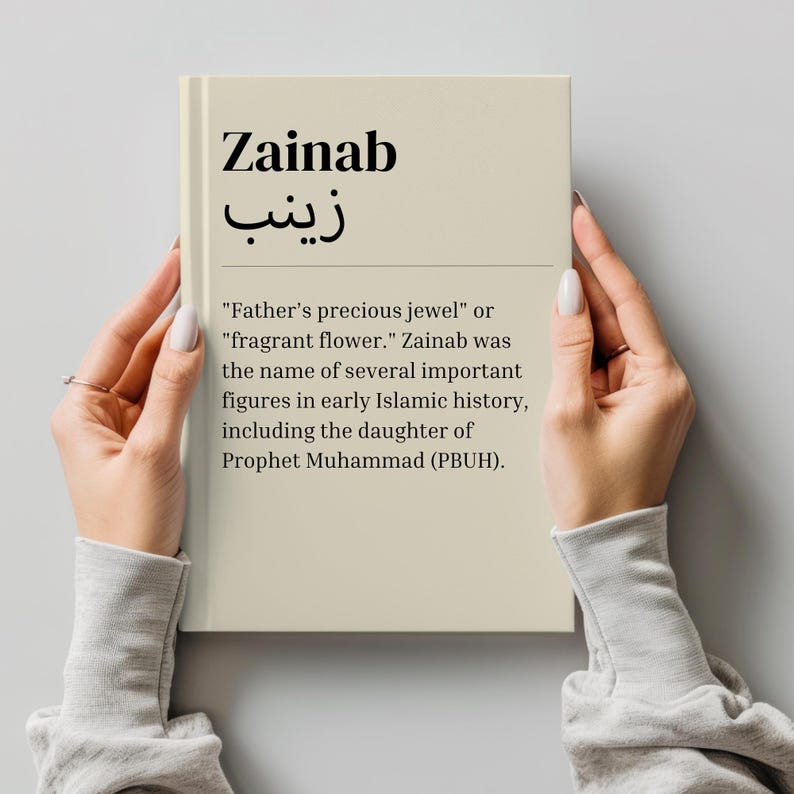 May include: A beige book with the word "Zainab" in black text and the Arabic word "زينب" in black text. The book also includes the text "Father's precious jewel" or "fragrant flower." Zainab was the name of several important figures in early Islamic history, including the daughter of Prophet Muhammad (PBUH).