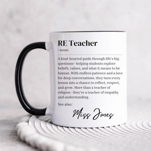 May include: White ceramic mug with a black handle. The mug has a black rim and the text "RE Teacher • noun A kind-hearted guide through life's big questions-helping students explore beliefs, values, and what it means to be human. With endless patience and a love for deep conversations, they turn every lesson into a chance to reflect, respect, and grow. More than a teacher of religion-they're a teacher of empathy and understanding. See also: Miss Jones" printed on it.