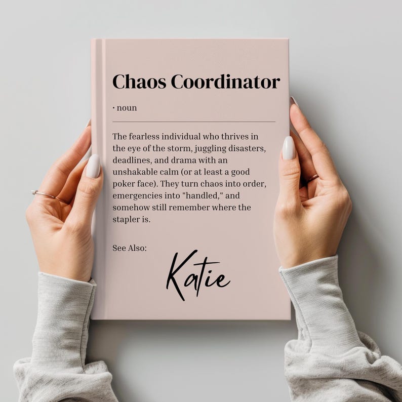 May include: A pink book with the title "Chaos Coordinator" and a definition of the term. The name "Katie" is written at the bottom of the page.