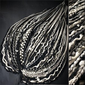 May include: A bundle of black, white, and gray dreadlocks. The dreadlocks are a mix of textures, including smooth, wavy, and braided sections. Some sections have small white beads. The background is a dark gray.