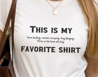 May include: White t-shirt with the text "This is my favorite shirt" and the words "horse feeding, manure scooping, hay slinging. I'll be at the barn all day" printed on it.