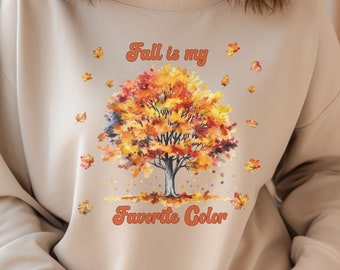 May include: A beige sweatshirt with a graphic of a fall tree with orange, yellow, and red leaves. The text "Fall is my favorite color" is printed below the tree.