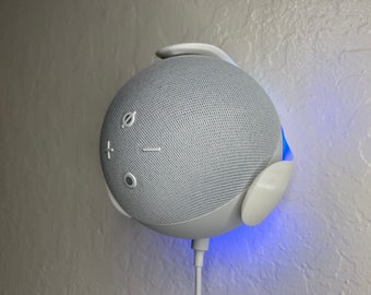 May include: A white smart speaker with a blue light ring around the base. The speaker has a fabric mesh covering and buttons for volume control and a microphone mute switch.