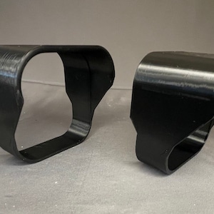 May include: Two black plastic 3D printed vent covers. The vent covers are designed to fit over a rectangular vent opening.