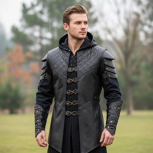 Puede incluir: Chaqueta con capucha de cuero negro con detalles acolchados en los hombros, el pecho y las mangas. La chaqueta presenta cierres decorativos y un corte largo y entallado. Las mangas son largas y ajustadas, con elementos decorativos adicionales.