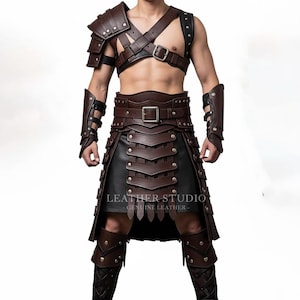 Könnte beinhalten: Ein braunes Leder-Rüstungsset mit Schulterschutz, Brustgurten, Gürtel, Rock und Armschützern. Die Rüstung hat Metallnieten und Schnallen. Der Rockboden ist aus schwarzem Leder. Der Text "LEATHER STUDIO - GENUINE LEATHER -" ist sichtbar.
