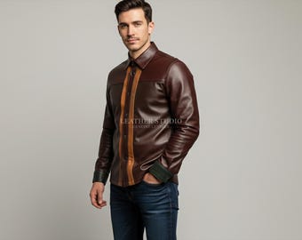 May include: A brown leather shirt with a collared neckline and long sleeves. The shirt features a vertical tan stripe down the front and green accents on the cuffs. The model is wearing blue jeans.