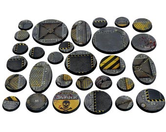 May include: A collection of miniature bases with a metallic, industrial design. The bases vary in size and shape, featuring textures like grates, panels, and hazard stripes. Some bases have "DANGER" and skull symbols, while others have blood splatter details.