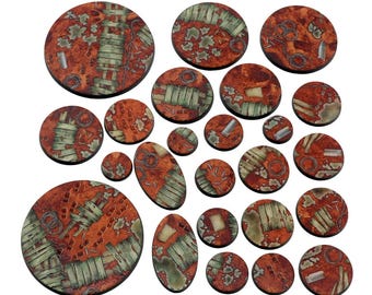 May include: A collection of miniature bases in various sizes and shapes. The bases feature a weathered, rusty orange color with patches of green and gray, suggesting a post-apocalyptic or fantasy theme. The bases are designed for tabletop gaming.