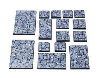 May include: A collection of twelve rectangular and square tiles featuring a blue and grey cobblestone pattern. Each piece has a distinct stone texture with dark grout lines, arranged in various sizes to form a modular set of terrain components.