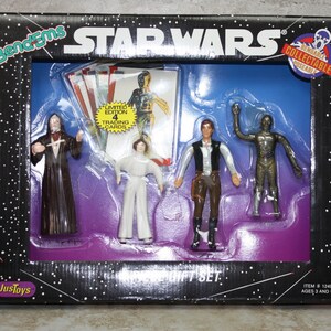 Peut inclure: Un coffret cadeau BendEms Star Wars comprenant quatre figurines pliables : Dark Vador, Princesse Leia, Han Solo et C-3PO. Le coffret comprend quatre cartes à collectionner en édition limitée. La boîte est noire avec des étoiles blanches et le texte "STAR WARS" en blanc.