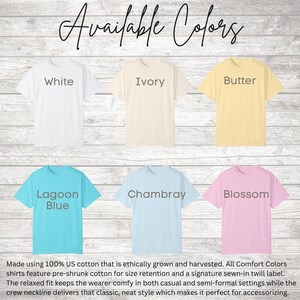 May include: A display of t-shirts in various colors: white, ivory, butter, lagoon blue, chambray, and blossom. The text "Available Colors" is at the top. The shirts are made of 100% US cotton.