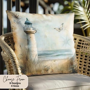 May include: A decorative throw pillow with a vintage-inspired design featuring a lighthouse on a sandy beach with a butterfly flying overhead. The pillow has a light blue, beige, and brown color scheme.