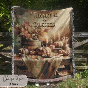 May include: Woven throw blanket with a fall harvest scene. The blanket features pumpkins, leaves, and the text "Thankful & Blessed." The blanket has a fringed edge and the text "Choose From 3 Sizes" at the bottom.