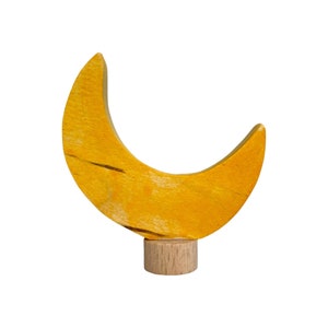 以下が含まれることがあります： 自然な木の台座が付いた黄色の木製の三日月。月は明るい黄色に塗られており、わずかにざらざらした表面をしています。