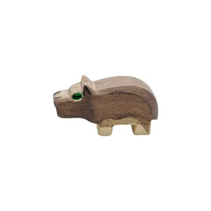 May include: A wooden toy animal, a brown and gray hippopotamus with green eyes. The toy is made of wood and has a simple, hand-crafted look.