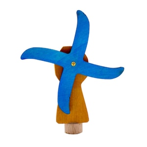 May include: A small wooden windmill with blue blades and a brown base. The windmill is a toy or decoration.