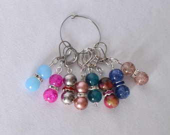 Pode incluir: Conjunto de seis marcadores de ponto coloridos com anéis de metal prateados. Os marcadores são feitos de contas de vidro com diferentes texturas e cores, incluindo rosa, azul, verde e prata.