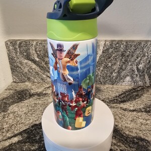 May include: A cylindrical water bottle featuring a colorful design with characters from a popular video game. The bottle has a blue handle and a green lid. The design includes various characters in a city and outdoor setting.