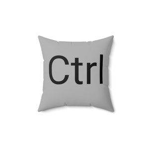 Könnte beinhalten: Ein graues Kissen mit dem Wort "Ctrl" in Schwarz bedruckt.