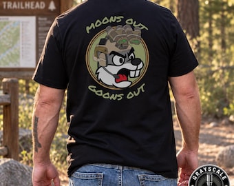 Może przedstawiać: Czarny t-shirt z grafiką na plecach przedstawiającą wściekłego bobra z kreskówki w taktycznym hełmie z goglami noktowizyjnymi. Okrągły wzór zawiera napis MOONS OUT GOONS OUT jasnozielonymi literami wokół ilustracji bobra.
