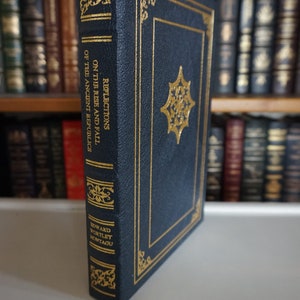 Puede incluir: Un libro de tapa dura azul marino con letras doradas y detalles decorativos. El t&iacute;tulo es "Reflexiones sobre el auge y la ca&iacute;da de las antiguas rep&uacute;blicas" de Edward Wortley Montagu.