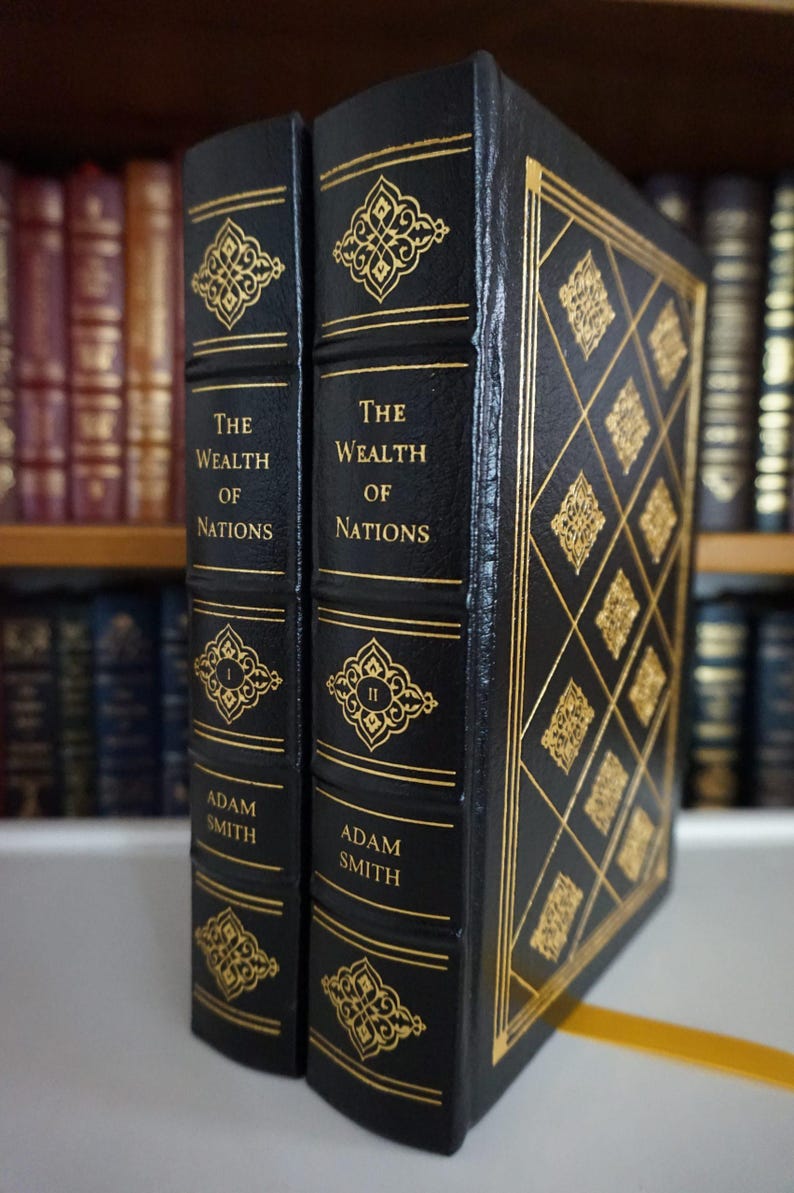 K&ouml;nnte beinhalten: Zwei gebundene B&uuml;cher mit dem Titel "The Wealth of Nations" von Adam Smith. Die B&uuml;cher sind schwarz mit goldenen Zierakzenten und Text. Die Buchr&uuml;cken weisen goldene Filigranmuster und die r&ouml;mischen Ziffern I und II auf.