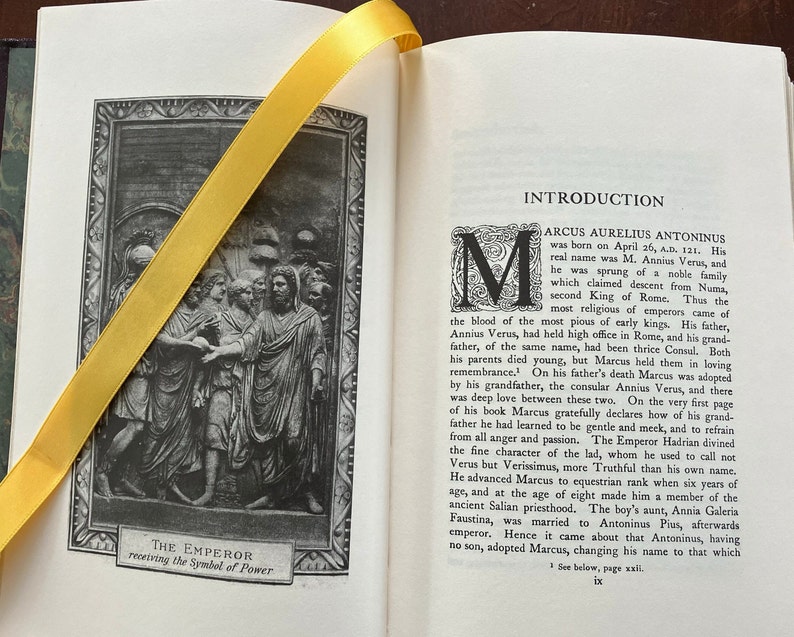 May include: A black and white image of a Roman emperor receiving the symbol of power. The image is from a book titled "The Emperor" and includes the text "The Emperor receiving the Symbol of Power".