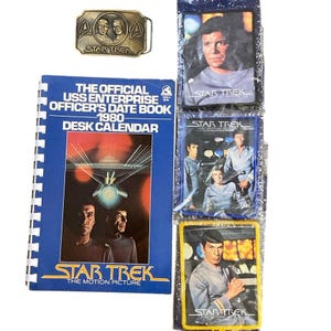 May include: A collection of Star Trek memorabilia including a brass belt buckle, a 1980 spiral-bound desk calendar titled The Official USS Enterprise Officer's Date Book, and three rectangular fabric patches featuring character imagery.