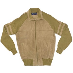 May include: A tan suede jacket with olive green knit sleeves and collar. The jacket has a full zipper closure and two vertical stripes on each sleeve. The jacket has a label on the collar.