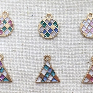 May include: Six gold-toned pendants with colorful geometric designs. Three are circular, and three are triangular. Each pendant features a grid pattern of various colors, including green, purple, white, and pink. The pendants have small loops for attaching to jewelry.