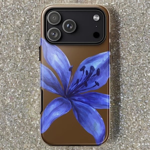 A brown iPhone case featuring a large blue lily flower graphic rests vertically on a textured stone surface.
