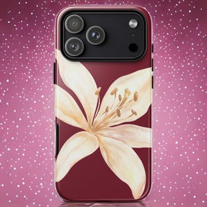Puede incluir: Funda de teléfono burdeos con un diseño floral en acuarela. La funda tiene un acabado brillante y una flor grande de color crema con estambres marrones. La funda del teléfono tiene un módulo de cámara negro.