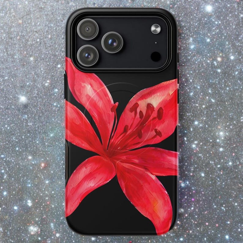 A black phone case with a red lily design is shown against a dark sparkling background.