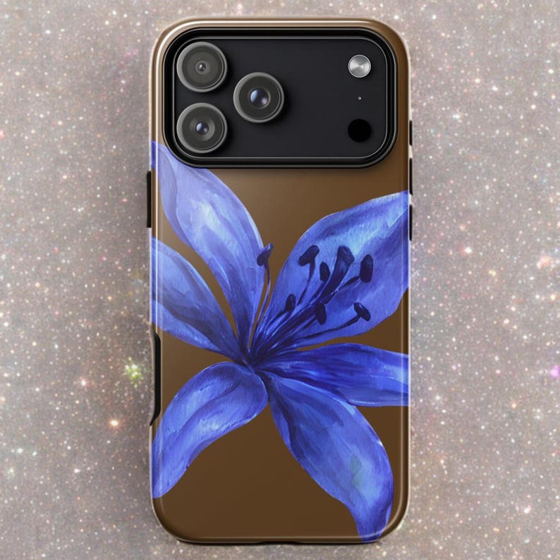 A brown iPhone case with a painted blue lily graphic is displayed vertically against a light speckled background.