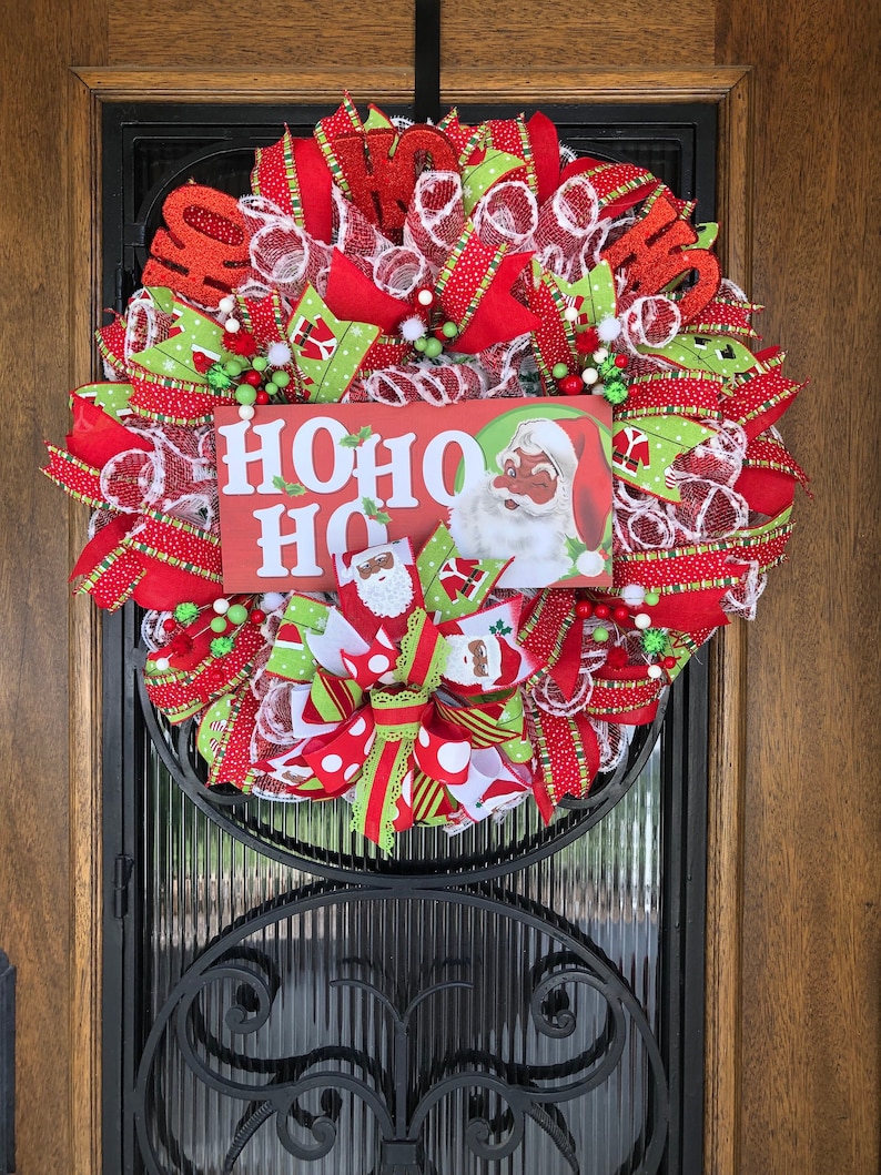Welcome your friends and guess with this super cute Santa wreath.  This wreath has beautiful red glittered Ho Ho Ho picks inserted across the top of the wreath to coordinate with the super fun wreath sign.
