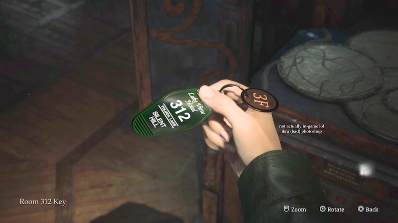 May include: A green hotel key card for room 312 at the Lakeview Hotel in Silent Hill. The key card has a gold ring and a 3F tag attached.
