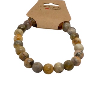 May include: A brown, beige, and white agate stone beaded bracelet. The bracelet is handmade and has a tag that says "Handmade with Love".