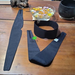 Puede incluir: Tres diademas de tela negra con cierres de velcro ajustables. Las diademas están hechas de un material suave y sedoso. El texto "Chu Silk Simple is the best" está impreso en una de las diademas.