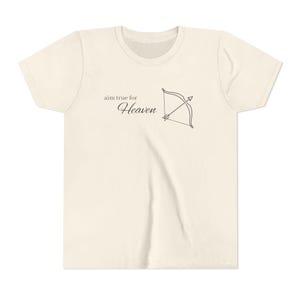 May include: Cream-colored t-shirt featuring the text "aim true for Heaven" and a bow and arrow graphic. The design is in black, centered on the chest. The shirt has a crew neck and short sleeves.