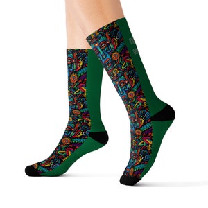 May include: Green knee-high socks with a vibrant, abstract design of faces, suns, and shapes. The socks have black toes and heels, with the text "D N" on the side. The pattern includes red, blue, yellow, and purple elements.